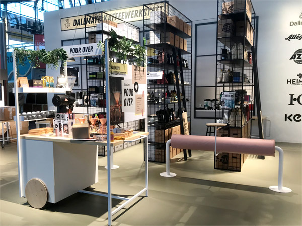 Messestand Kaffeewerkstatt, Stahlregale, Werkstattwagen, Klicklinoleum, geflieste Theke, Durchreiche, verputzte Kabine, Fenster, Anlehnhocker, Beistelltische